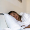 Image of sleeping woman in bed - get a more restful night's sleep with Alurx all-natural Melatonin Sleep Gummies